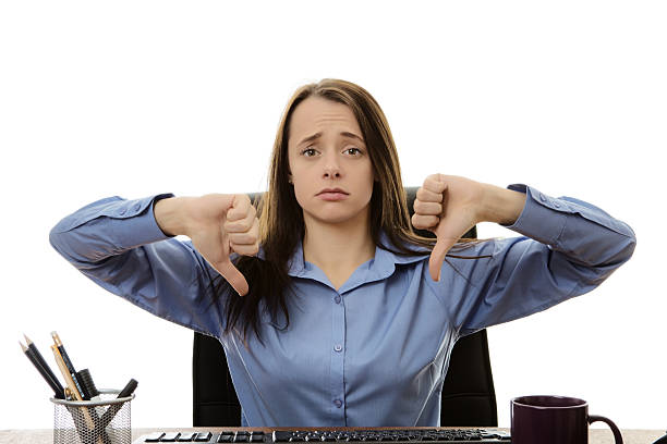 business woman sitting at a desk with her thumb down