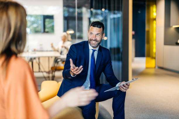 Teammate explaining branding strategies. Smiling businessman engaging in a lively conversation with a female coworker, showcasing effective communication and enthusiasm