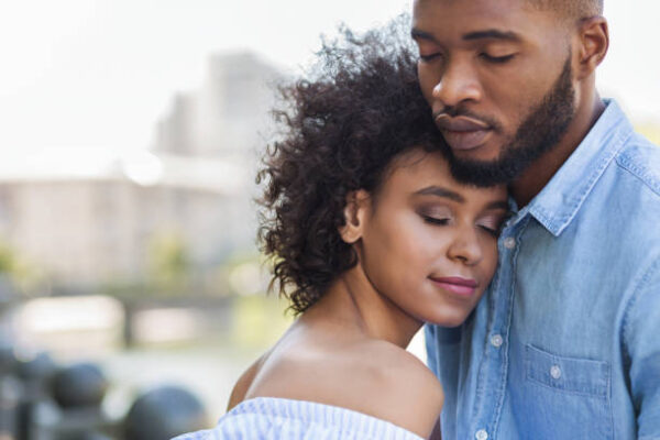 Tender black couple hugging with closed eyes outdoors