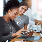 Shot of two young colleagues using a digital tablet together at work